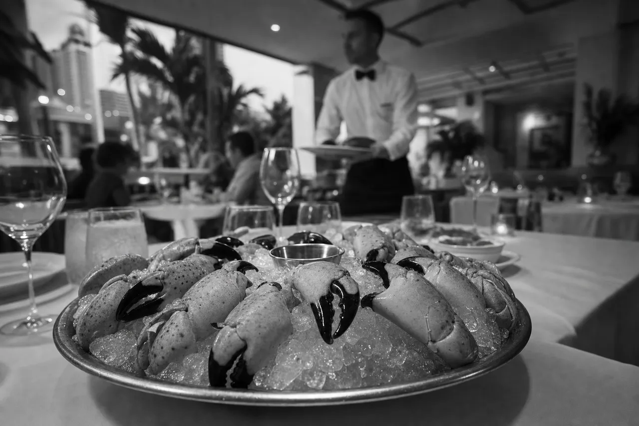 Black and white cinematic view of a seafood restaurant table with stone crab claws on crushed ice