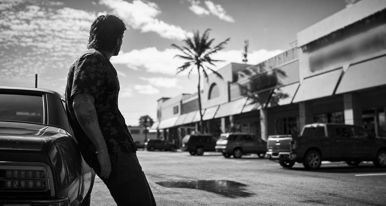 Black and white cinematic view of a strip mall with a shared parking lot, a row of awnings and one palm tree