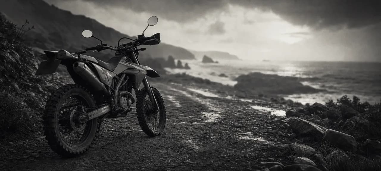 Black and white cinematic concept image of a nimble Japanese dual-sport motorcycle on a gravel coastal trail