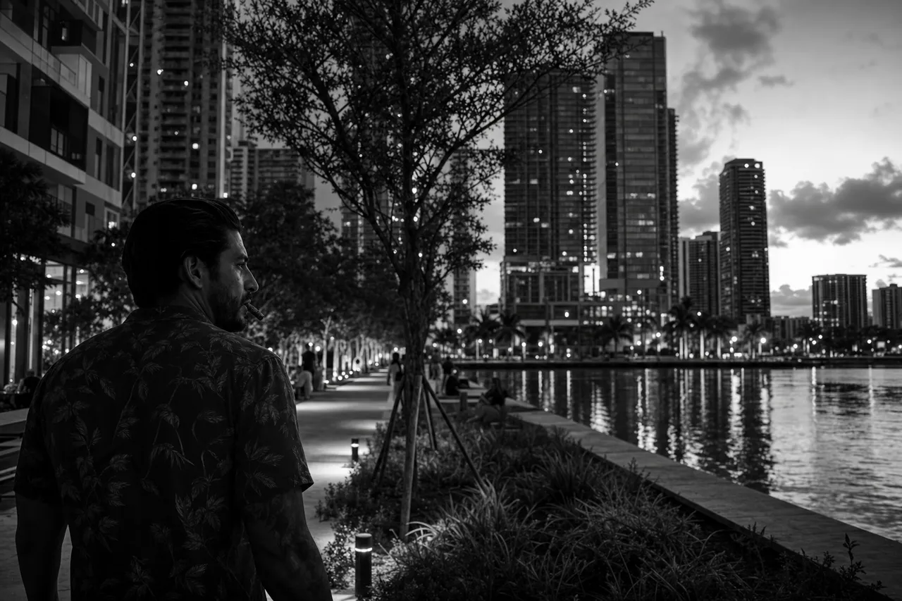Black and white cinematic view of a riverfront promenade with young trees and glass towers rising behind