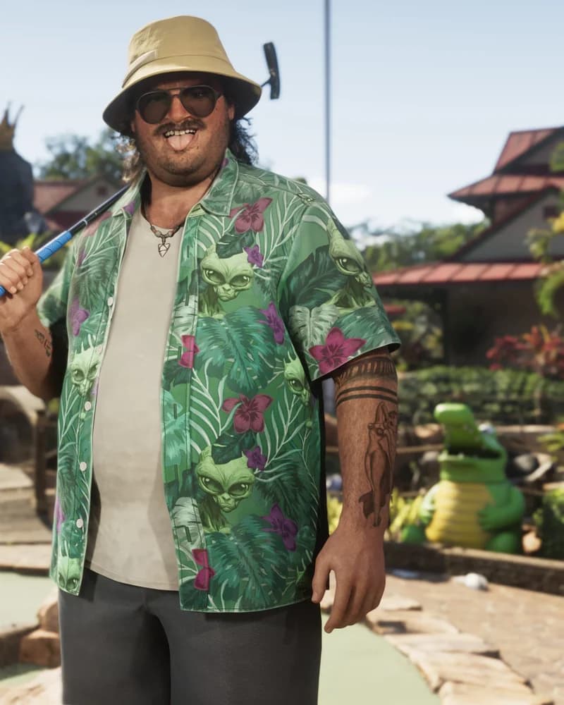 Cal Hampton at a tropical mini-golf course, wearing a green floral shirt and a beige bucket hat, holding a putter over his shoulder.