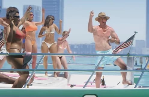 Shirtless middle-aged man in a straw hat dancing at a Vice Beach pool party, Trailer 1.
