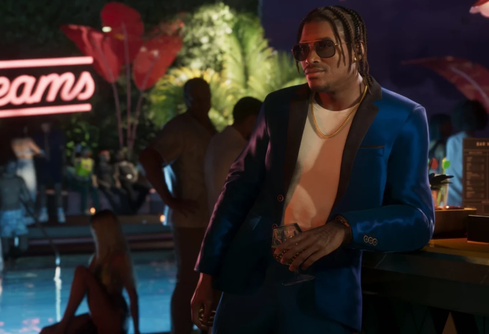 Dre'Quan Priest in a midnight-blue blazer at the Mai Dreams pool party, holding a cocktail, leaning on a bar.