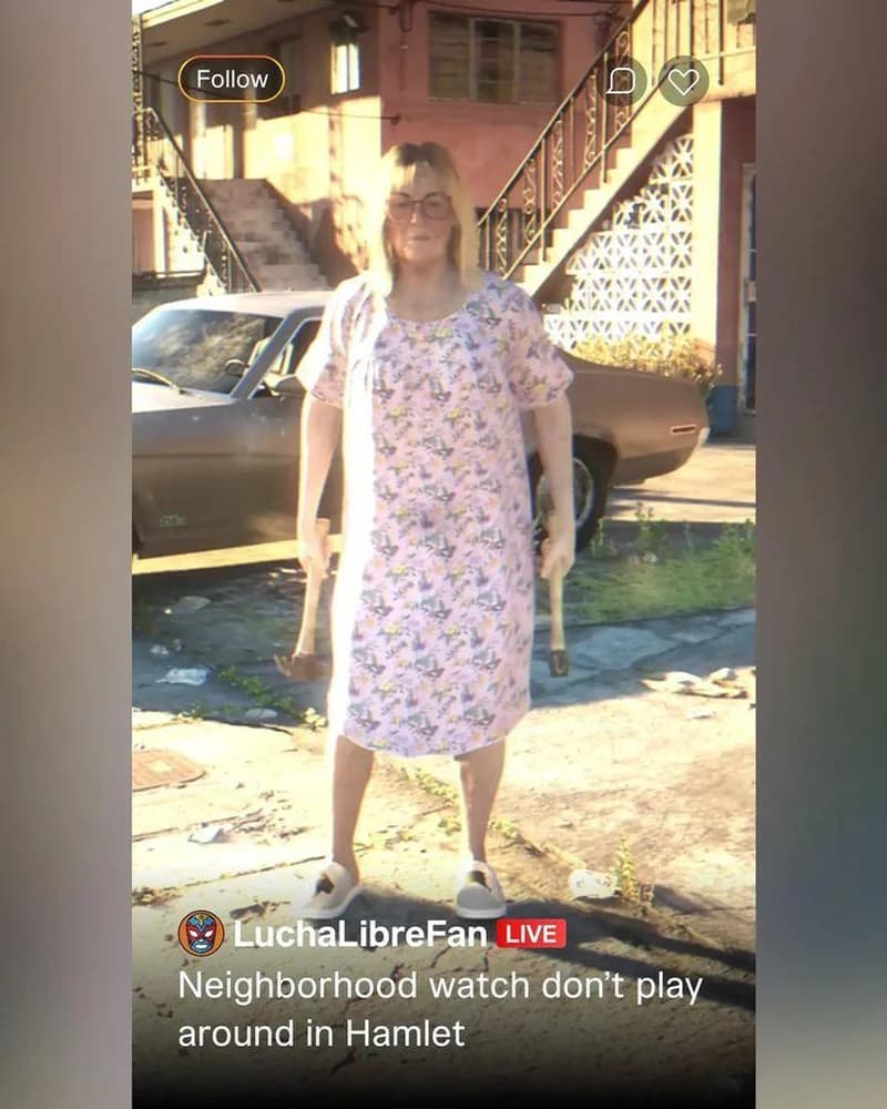 Middle-aged woman in a floral nightgown holding two hammers, mid-confrontation in a Hamlet driveway, framed inside a LuchaLibreFan livestream overlay.