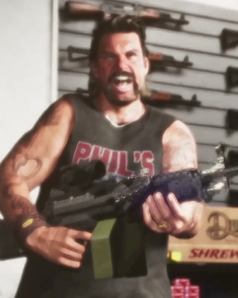 Phil yelling and holding a rifle inside his Ammu-Nation store, gun rack visible behind him, mustache and tank top.