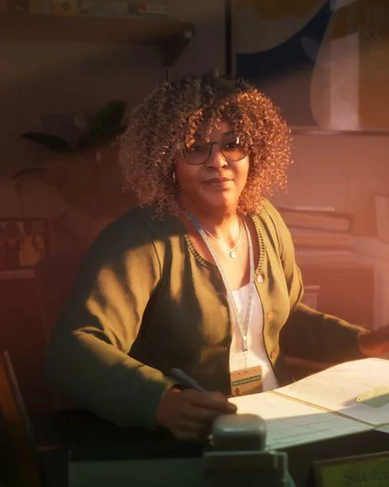 Stefanie G. seated across a desk from Lucia at the Leonida correctional facility, glasses and curly hair, lit warmly.