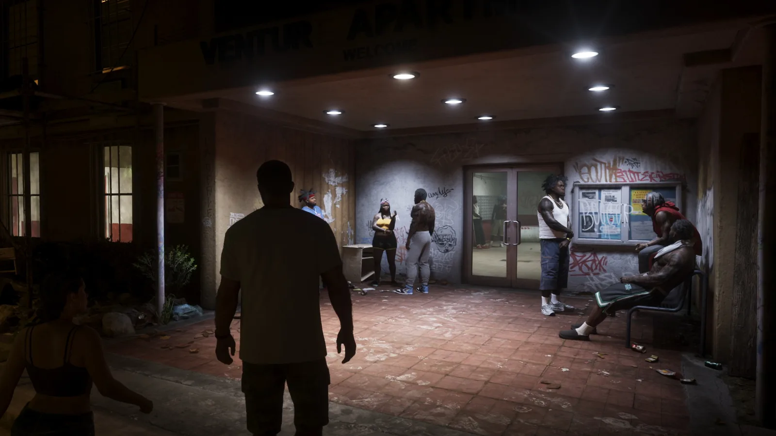 Jason walking towards the graffiti-covered entrance of the Venture Apartments at night in GTA 6