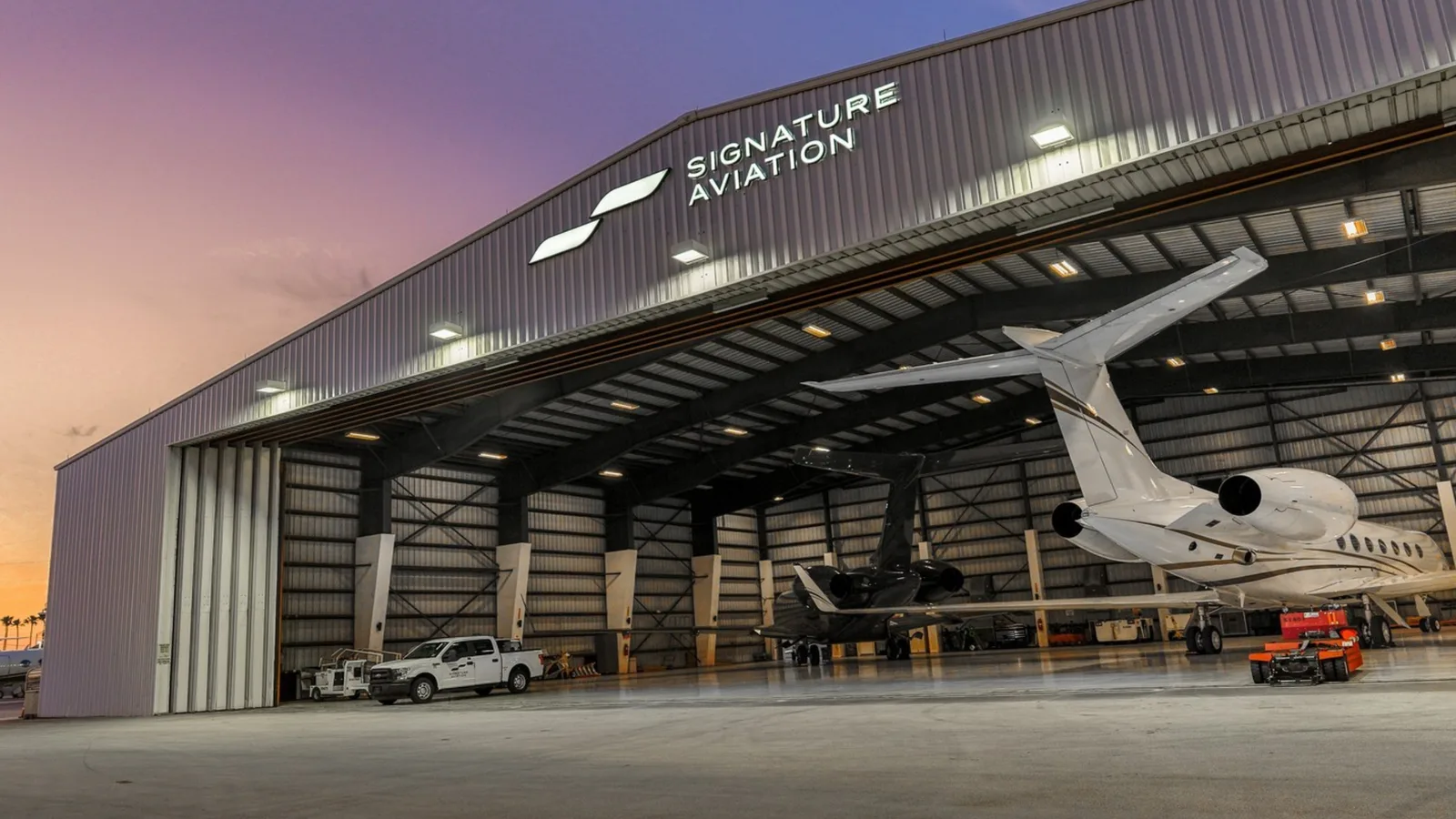 A private jet parked in a fixed base operator hangar at dusk