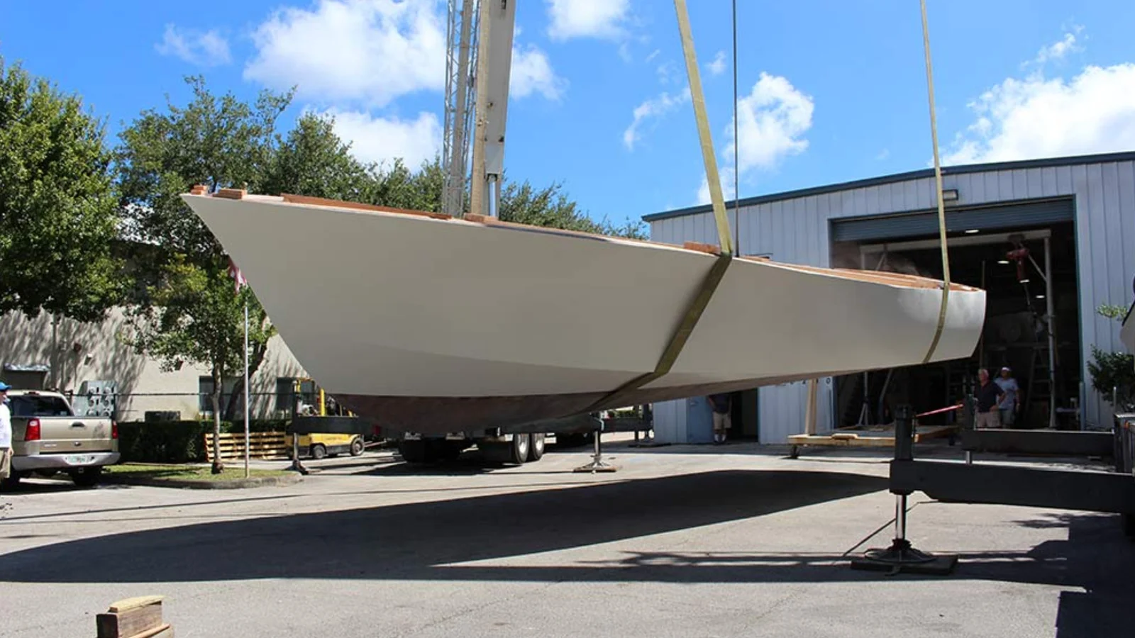 A fresh hull hanging in slings at a Florida boatyard