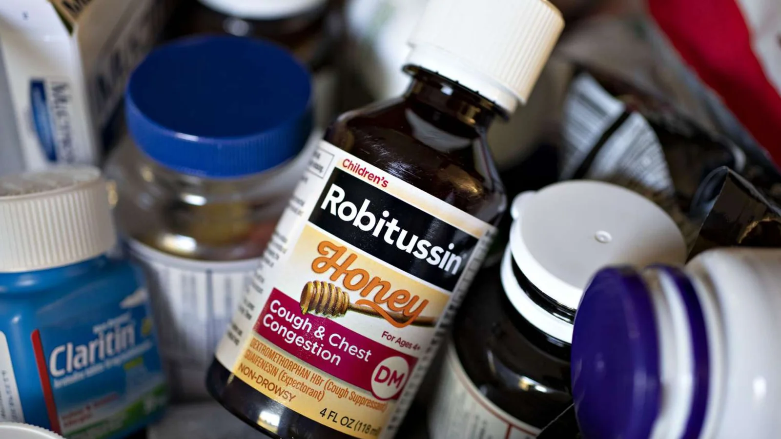 A bottle of Robitussin Honey cough syrup in a medicine cabinet