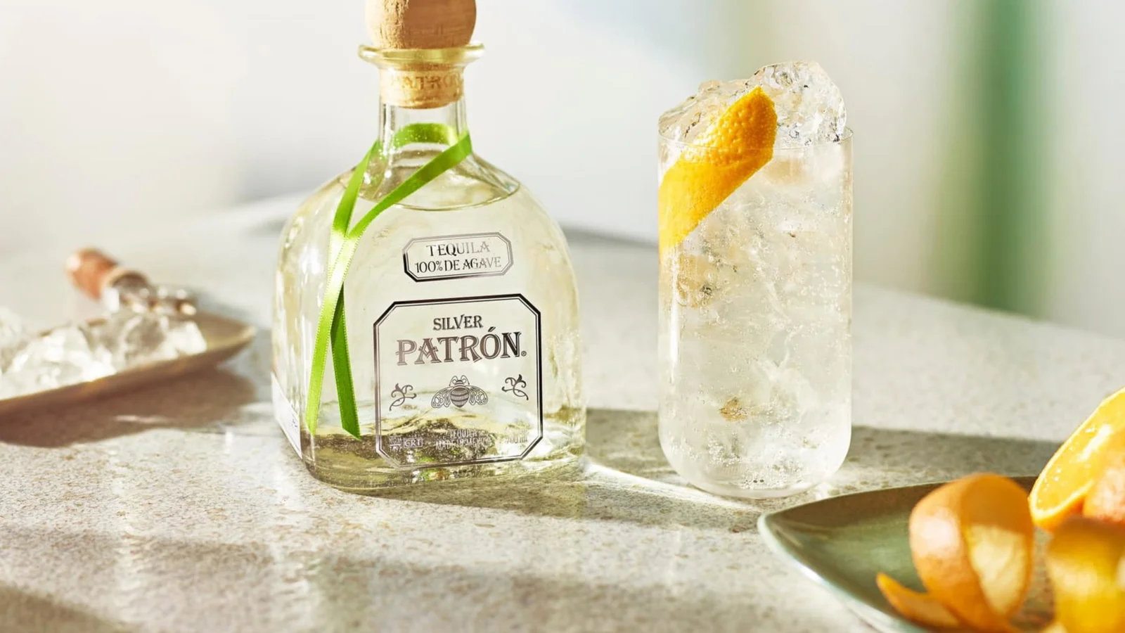 A bottle of Patrón silver tequila with a garnished cocktail