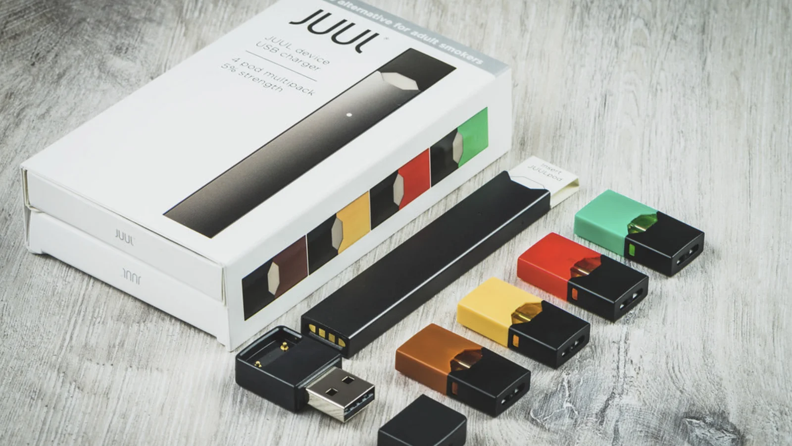 A JUUL vape device kit with coloured pods