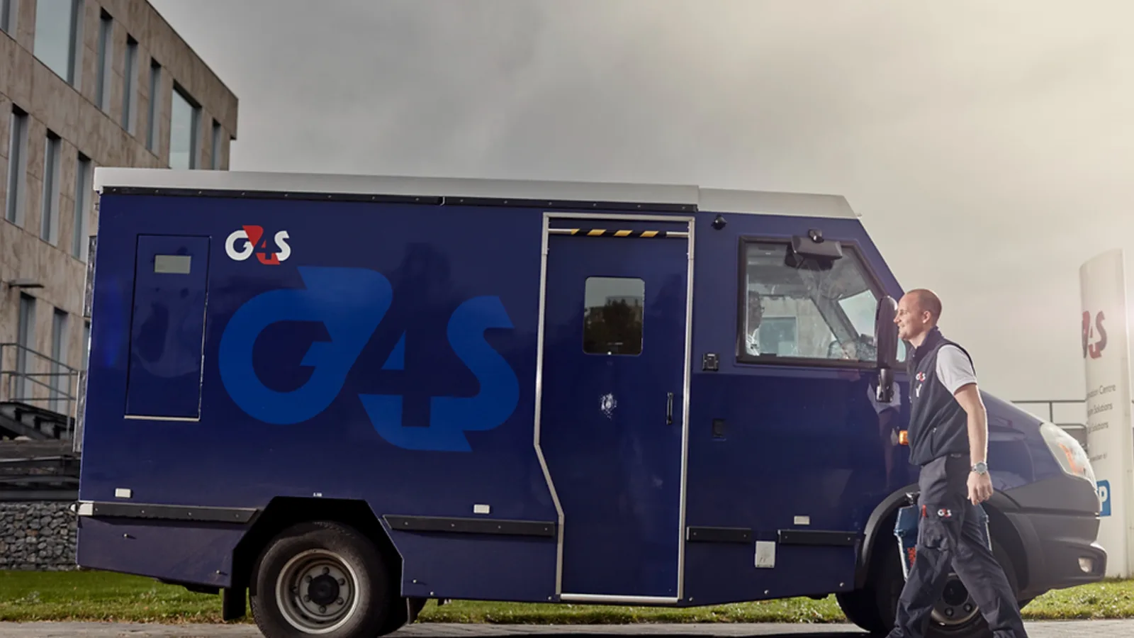 A guard closing the door of a blue armoured cash van