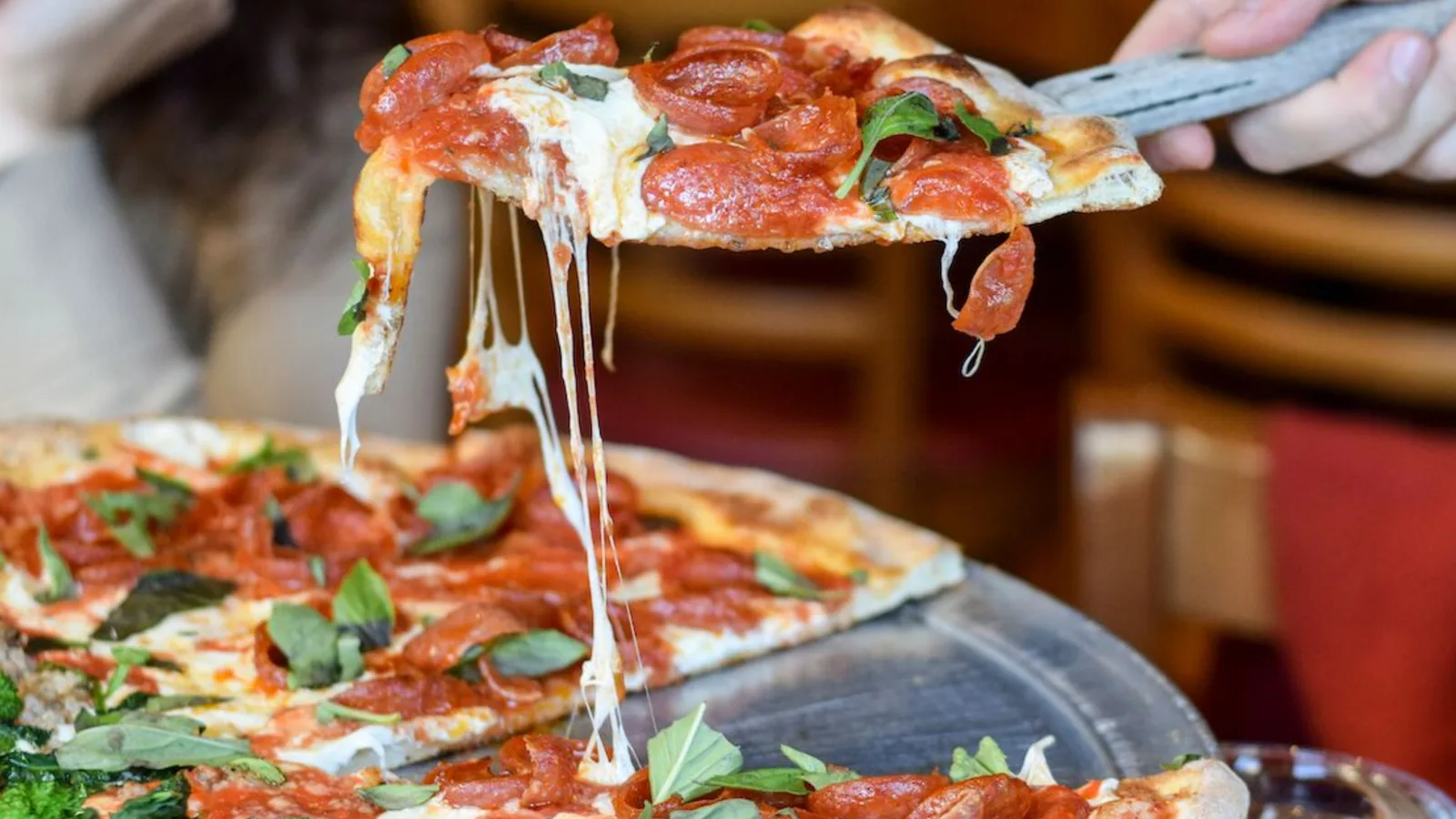 A cheese pull slice lifted from a pepperoni pizza