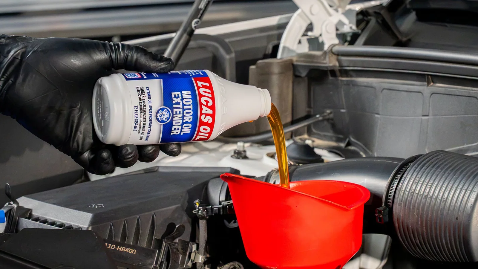 Lucas Oil poured into an engine through a red funnel