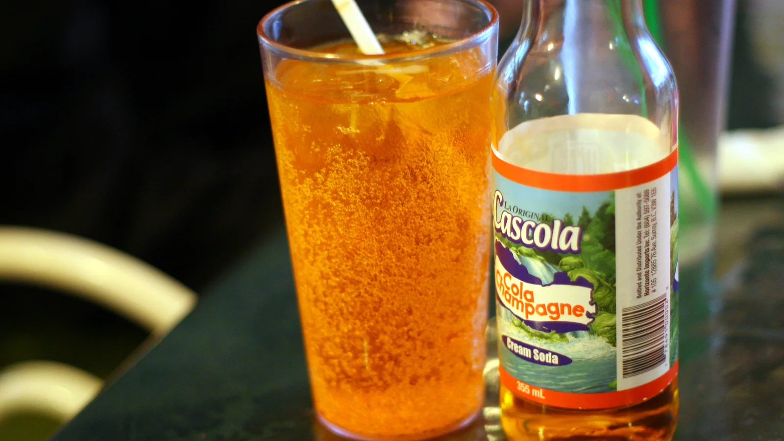 A glass of Fruit Champagne soda poured beside the bottle