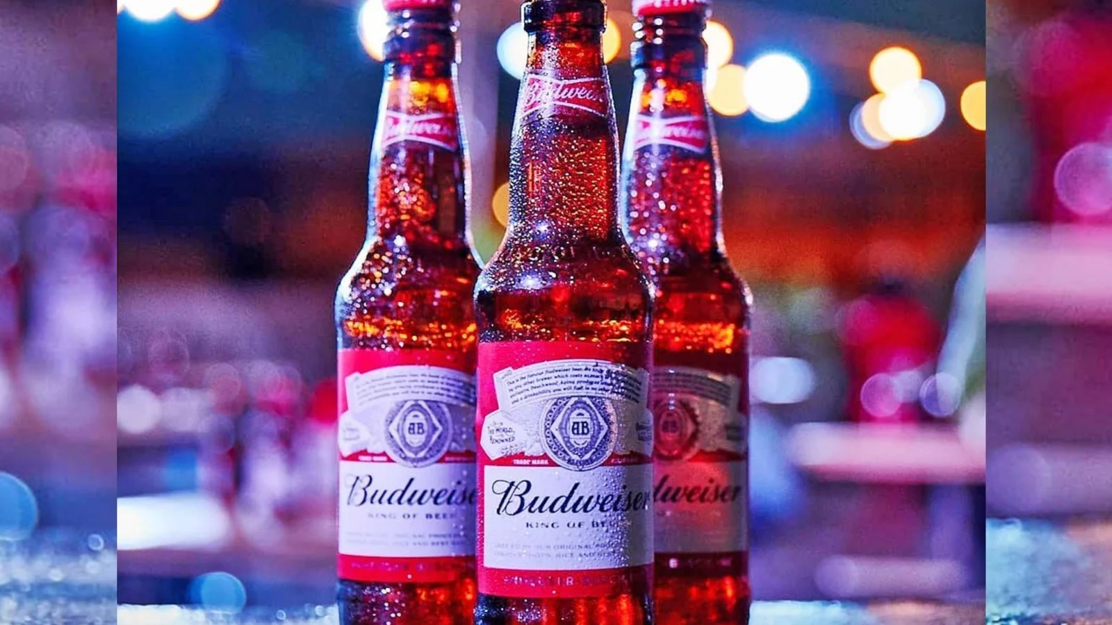 Budweiser bottles on a bar counter under neon light