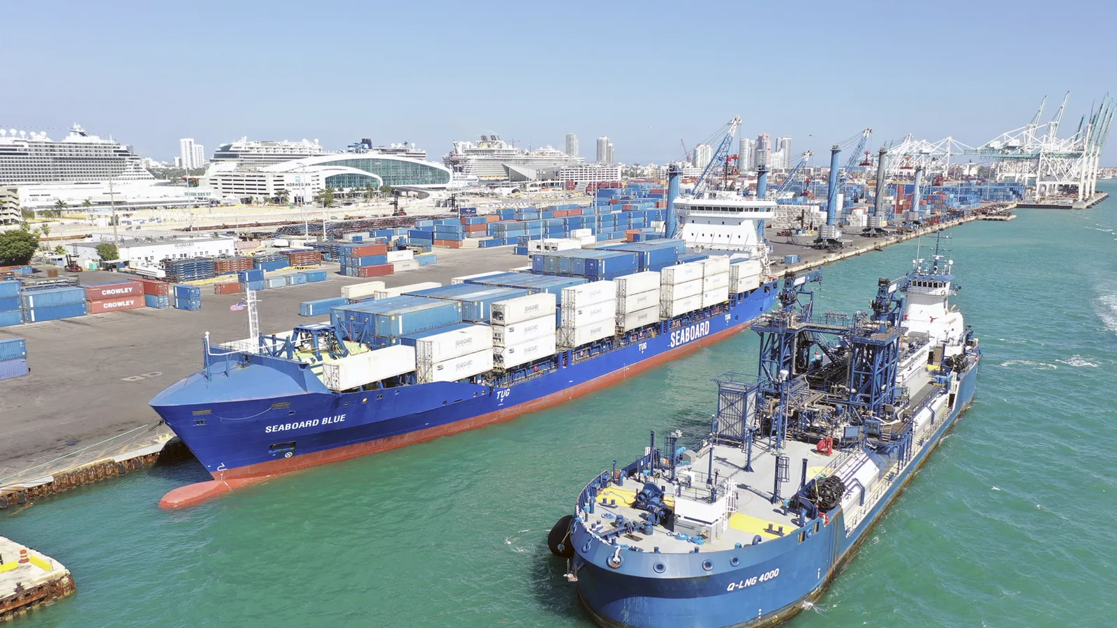 A container ship guided by tugs into a Florida port