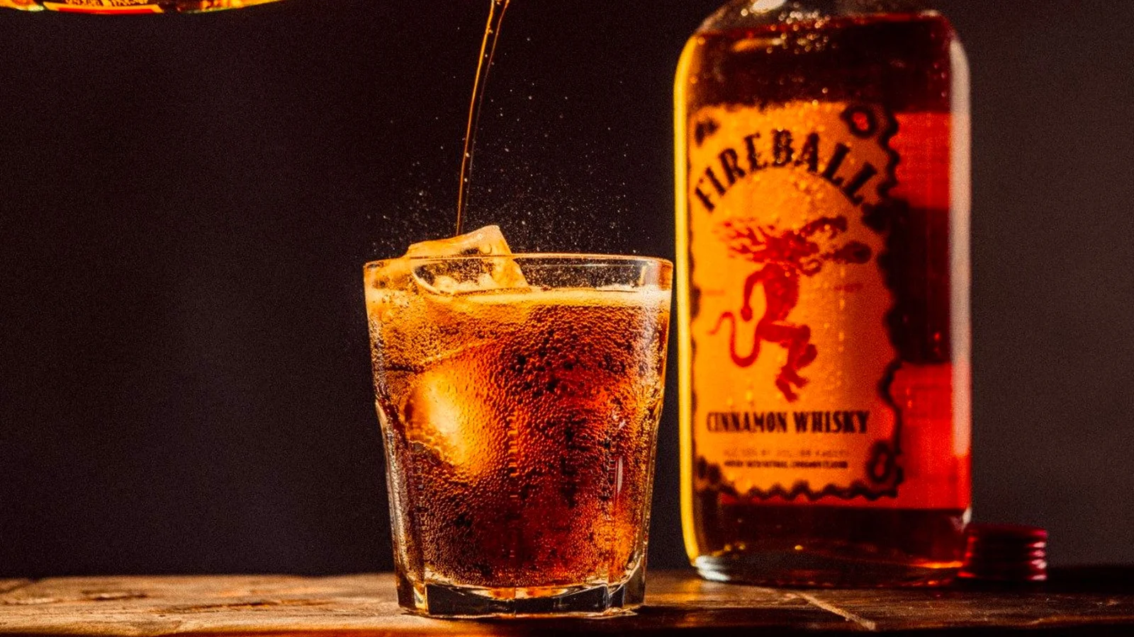 A bottle of Fireball cinnamon whisky beside a glass with ice