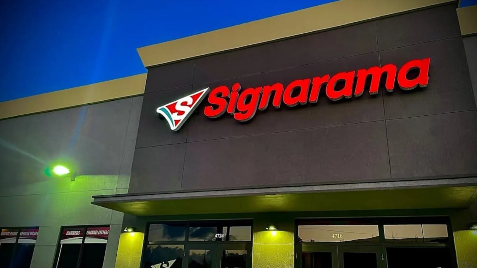 An illuminated sign maker’s storefront at night