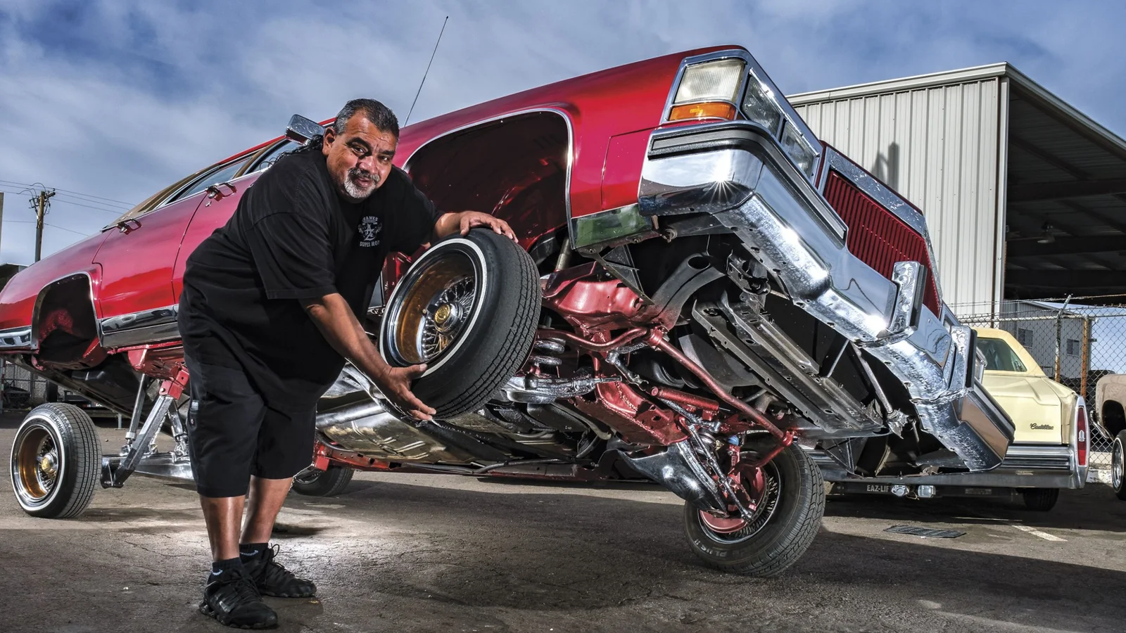 A lowrider truck up on three wheels with its owner beside it