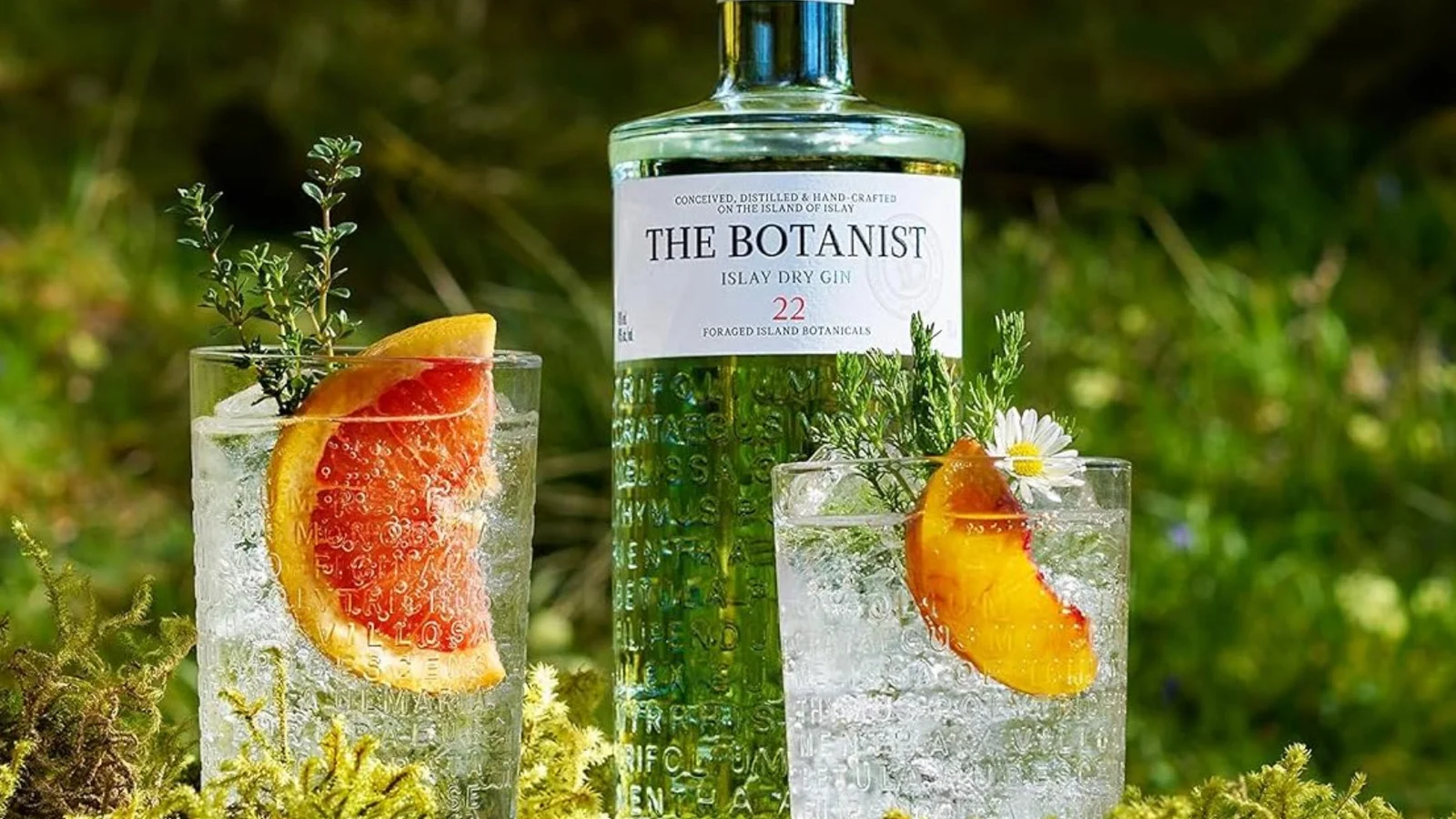 A bottle of The Botanist gin beside garnished glasses