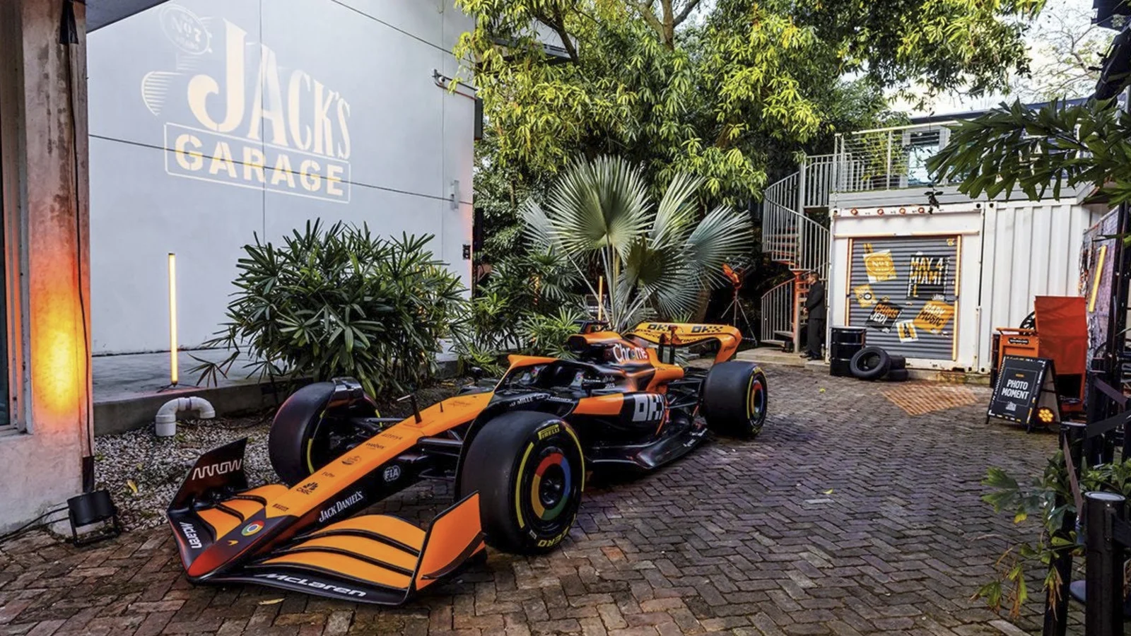 A sponsor liveried single seater parked outside a garage