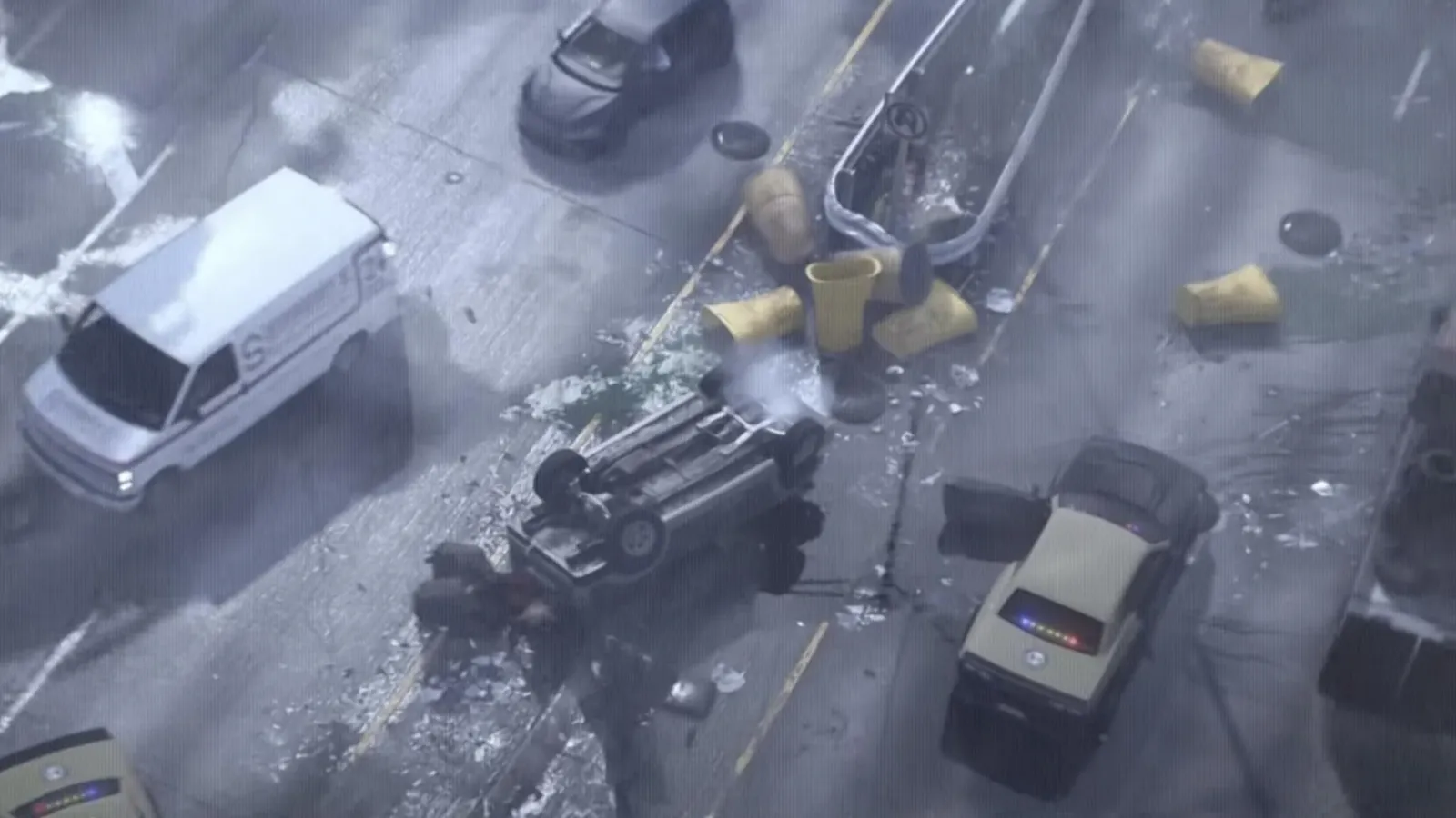 Aerial view of a GTA 6 crash scene with a flipped car, scattered barrels, a downed traffic pole and police arriving