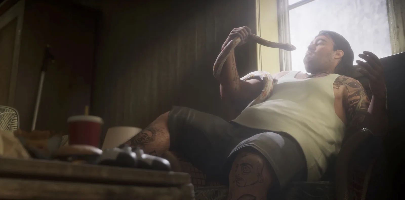 A tattooed man reclines with a snake above his face beside fast food in the GTA 6 launch trailer