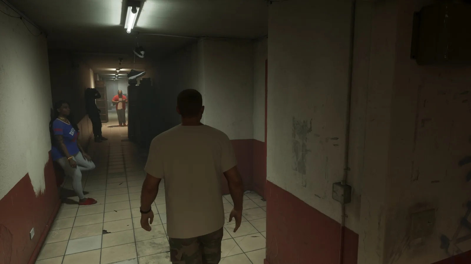 A dim corridor inside the Venture Apartments with residents leaning against the walls