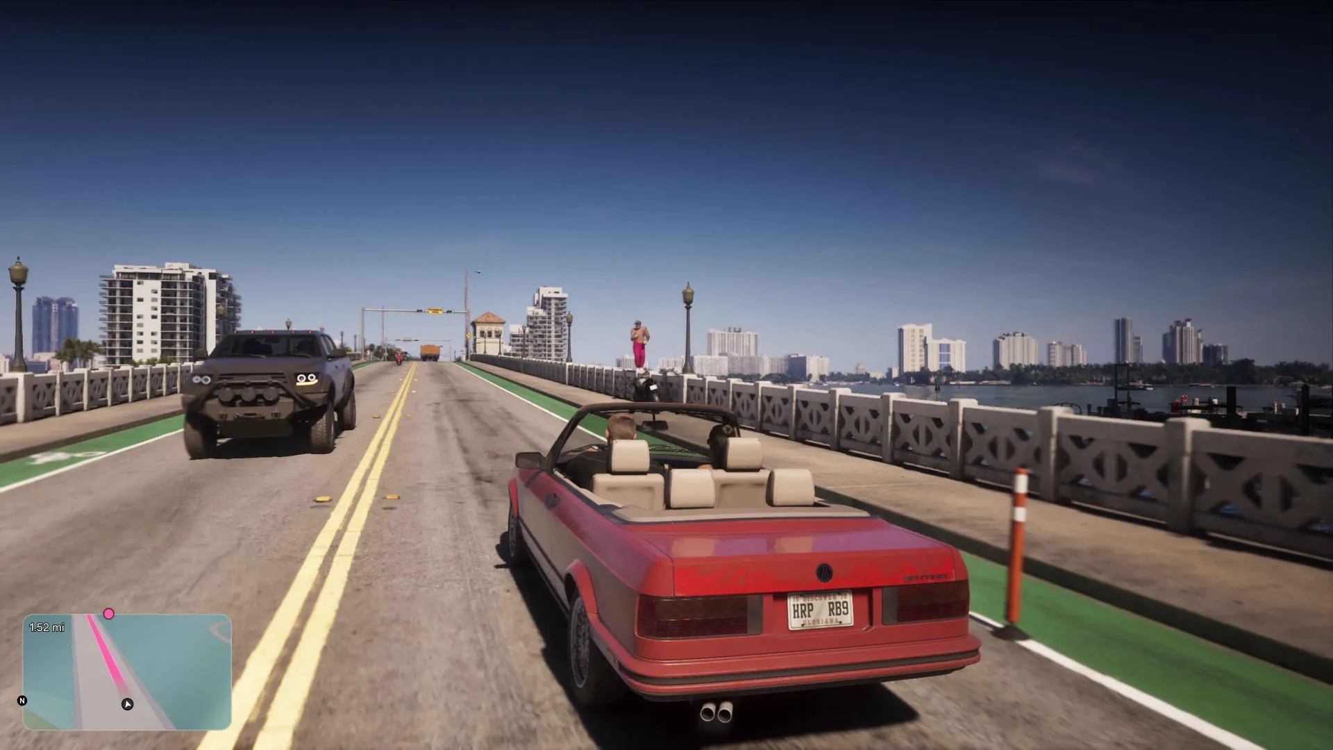 A red convertible crossing a causeway bridge over open water toward the Vice City skyline at midday in GTA 6