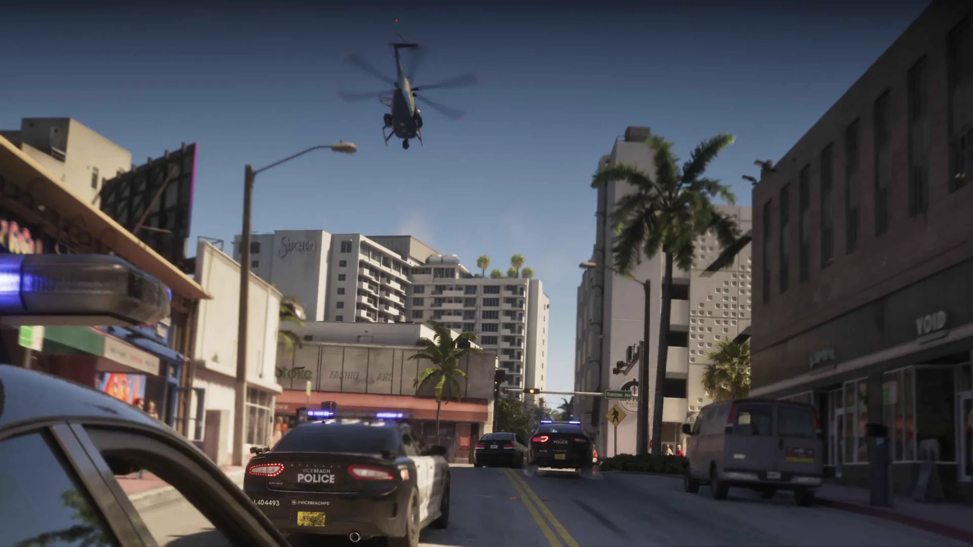 A police helicopter hovers over a GTA 6 intersection while Vice Beach Police cruisers converge past palm trees, storefronts and a parked van