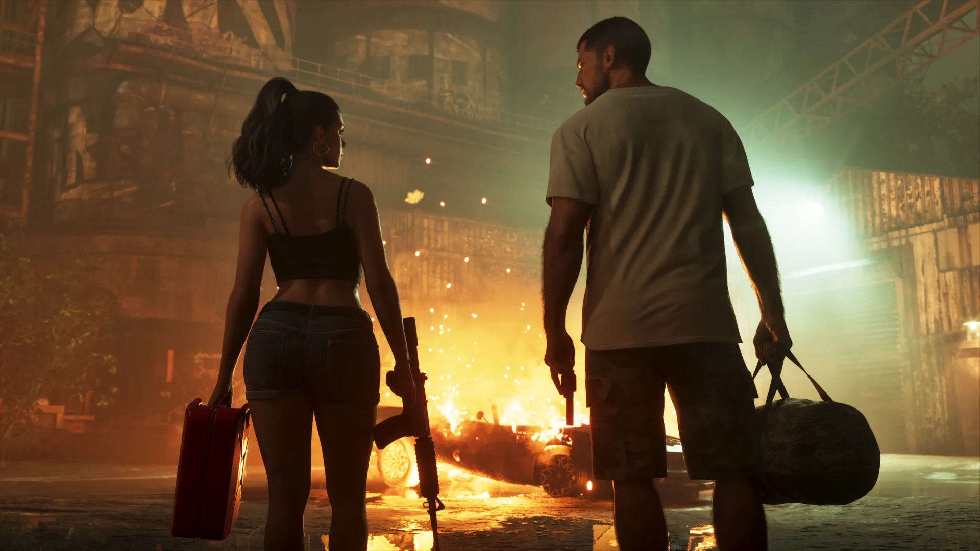 Lucia and Jason seen from behind carrying a case and a duffel bag past a burning car in an industrial yard in GTA 6