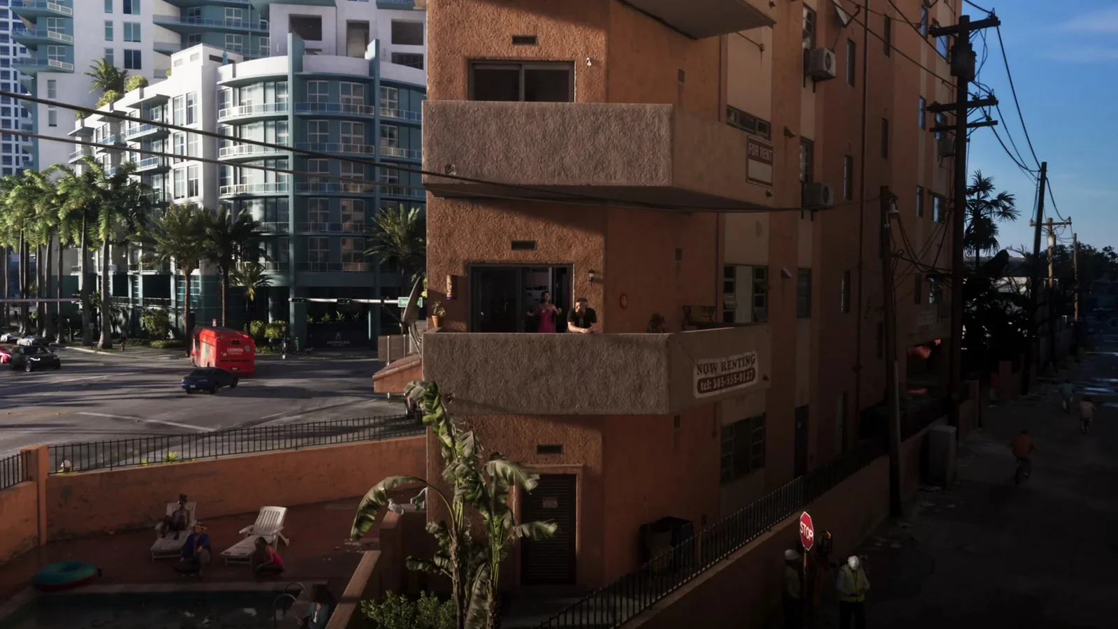 Jason and Lucia stand on the balcony of a coral coloured apartment block in GTA 6 with Now Renting signs on the wall and a light blue tower behind.