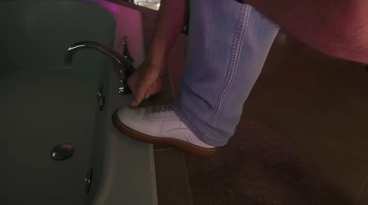 White trainer by the bathtub tap