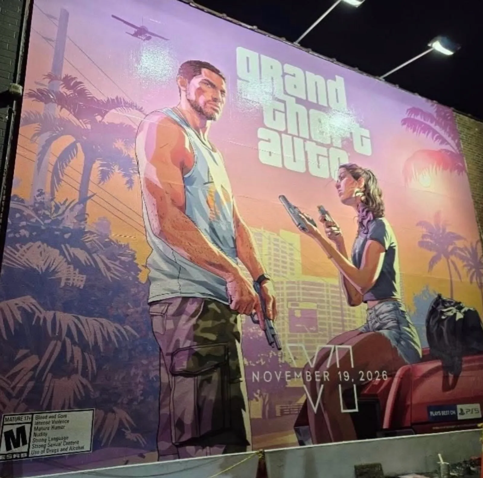 A finished hand-painted GTA 6 wall mural of Jason and Lucia with the November 19, 2026 date and ESRB rating