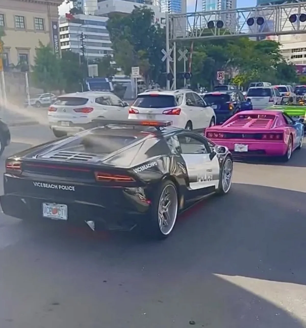 A black and white Vice Beach Police Lamborghini Huracan driving through Miami traffic with a pink sports car behind