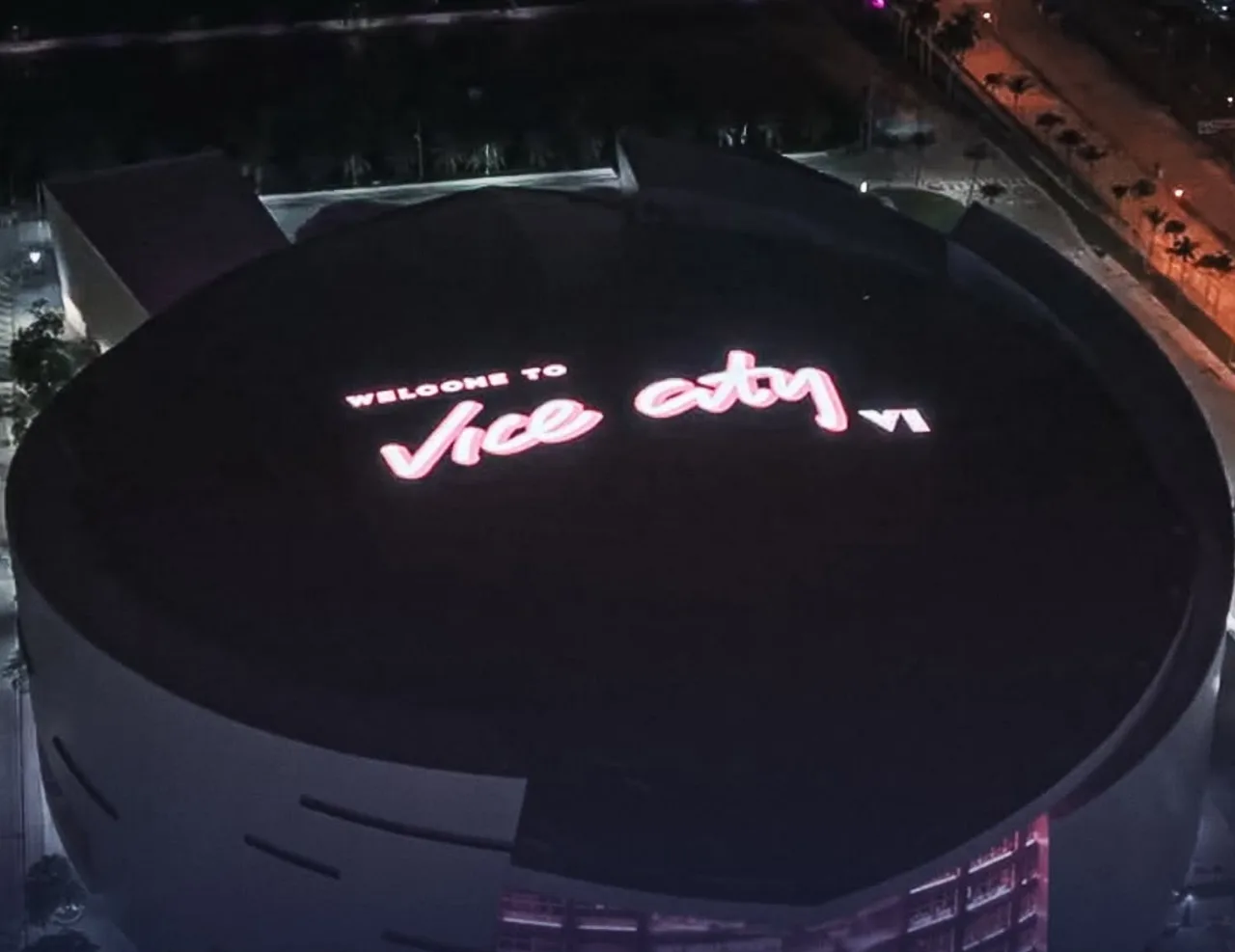 Aerial night view of the Welcome to Vice City sign lit on the roof of Kaseya Center