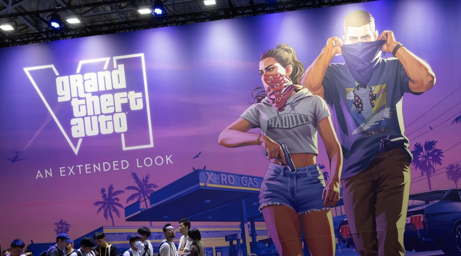 Visitors walk beneath a giant Extended Look banner showing Jason and Lucia at a games event