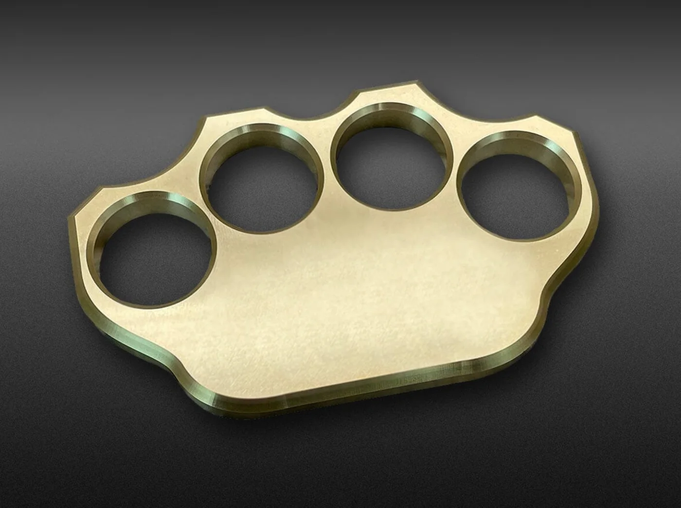 Polished brass knuckles with four finger rings on a dark background, the real-world basis for the GTA 6 Knuckle Dusters.
