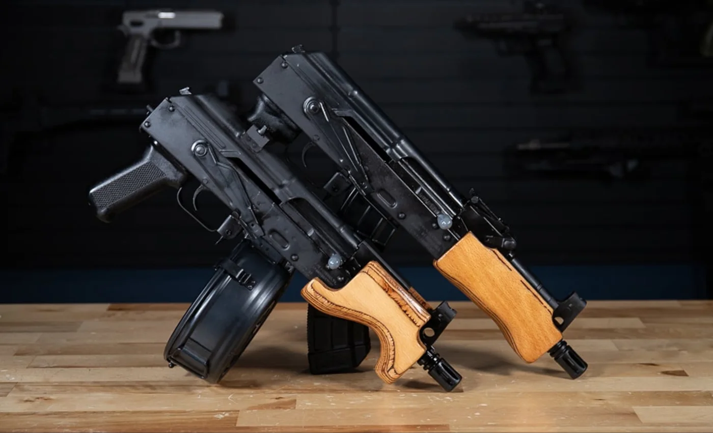 Two Micro Draco AK pistols with wooden handguards standing upright on a wooden bench, the real-world basis for the GTA 6 compact rifle.