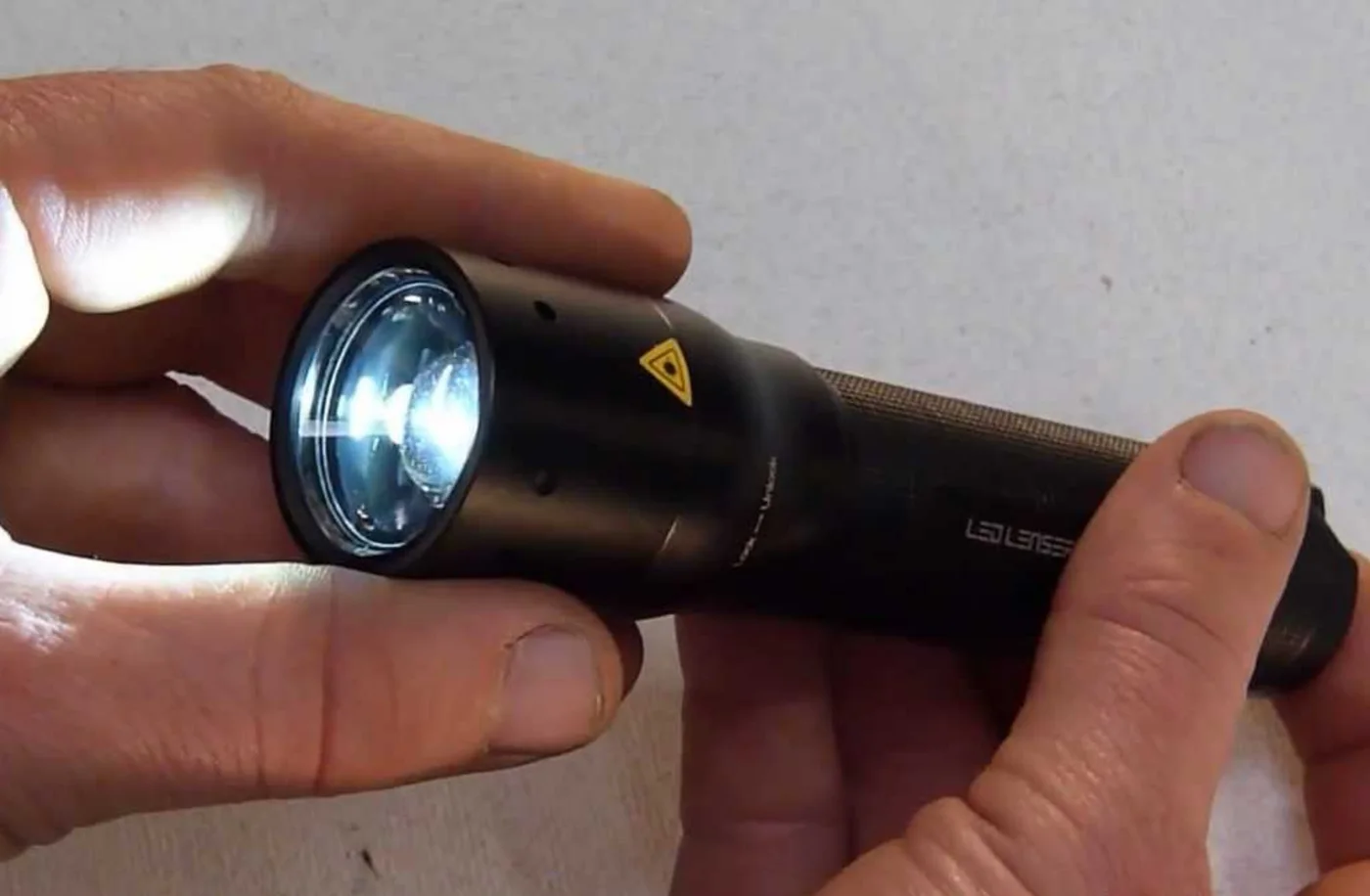 Hand gripping a lit Ledlenser M7R torch with a cool white beam, the real-world basis for the Vom Feuer Flashlight.